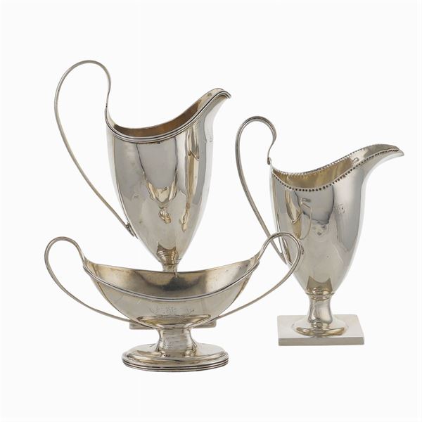 Two milk jugs and a silver sauce boat