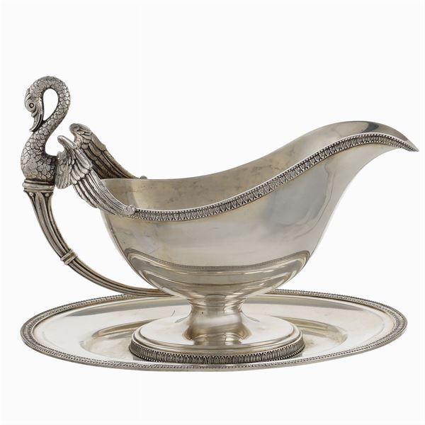 An italian silver sauce boat resting on an oval tray
