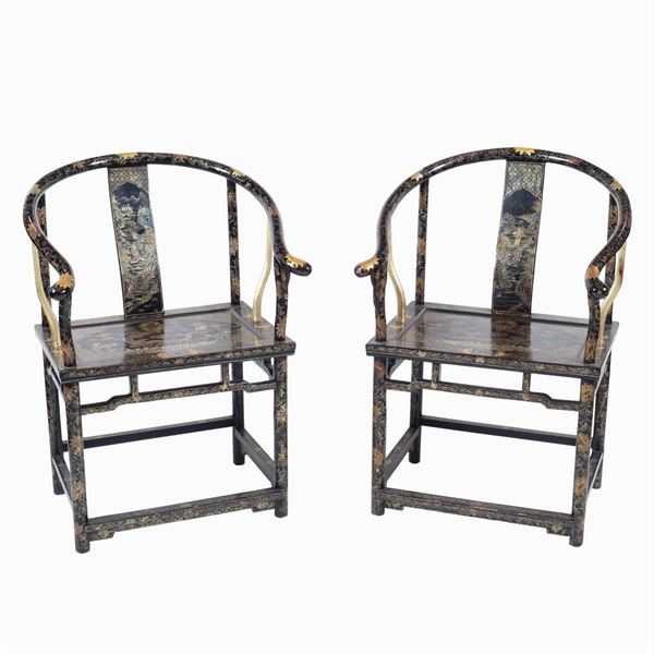 A pair of armchairs in black and gilt lacquered wood